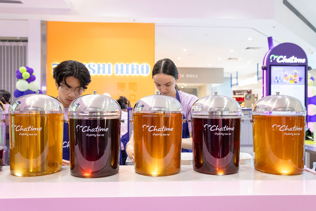 Beverage preparation at Chatime, showcasing tea containers and staff.