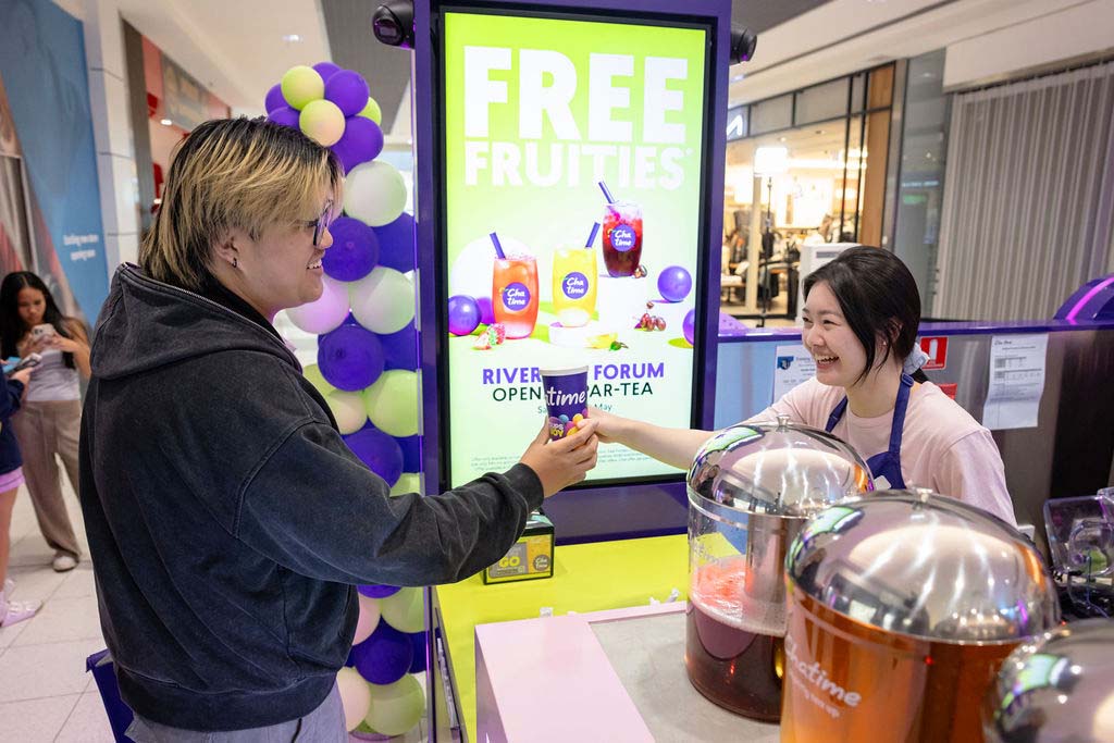 Customer interacting with staff at a Chatime store, promoting free fruity beverages.